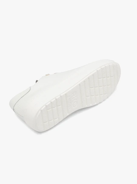 Weiße halbe Sportschuhe auf leichtem Boden