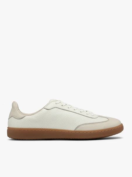 Cremige, sportliche Halbschuhe auf einem flachen, beigen Untergrund