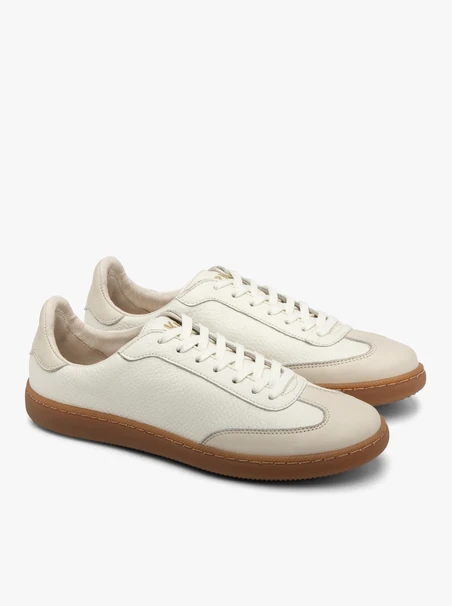 Cremige, sportliche Halbschuhe auf einem flachen, beigen Untergrund