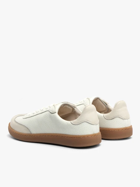 Cremige, sportliche Halbschuhe auf einem flachen, beigen Untergrund